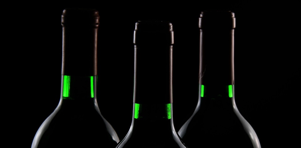 Drei Flaschen Merlot - Rotwein vor einem schwarzen Hintergrund.