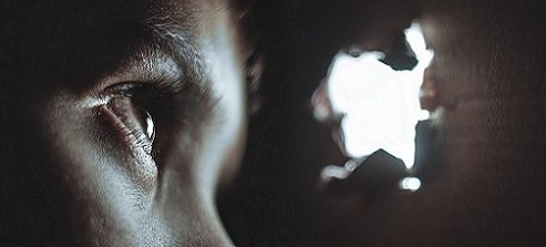 Heimlicher Zuschauer lugt durch ein Loch in einer Wand.