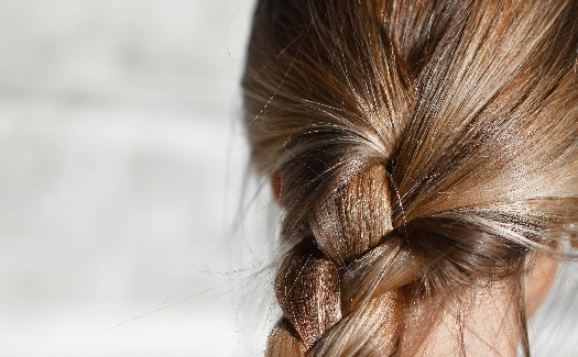 Frau mit dunkelblondem Haar und einem Zopf.