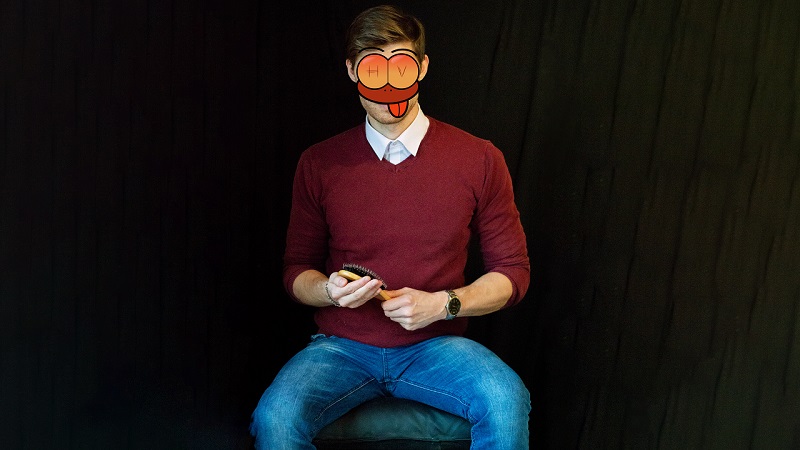 Spanking Sessions für Frauen (18+) in Bayern: Aktiver Spanko in rotem Pullover, weißem Hemd und blauer Jeans mit Armbanduhr sitzt auf einem Hocker mit einer Haarbürste aus Holz in der Hand und wartet auf eine weibliche Spankee, um sie übers Knie zu legen und ihr den nackten Hintern zu versohlen