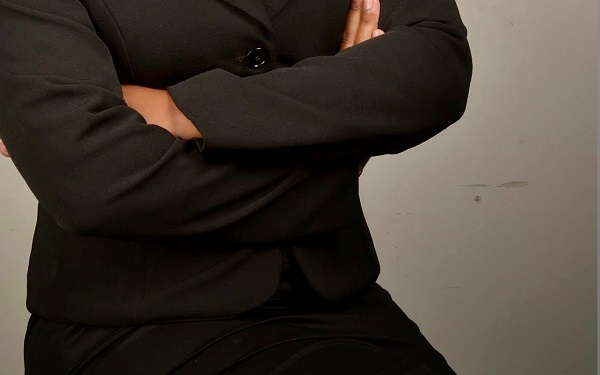 Strenge Frau in schwarzer Kleidung steht mit verschränkten Armen da