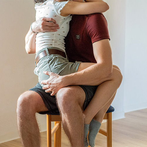 Aftercare nach Spanking: Junge Frau wird von einem Mann auf seinem Schoß getröstet